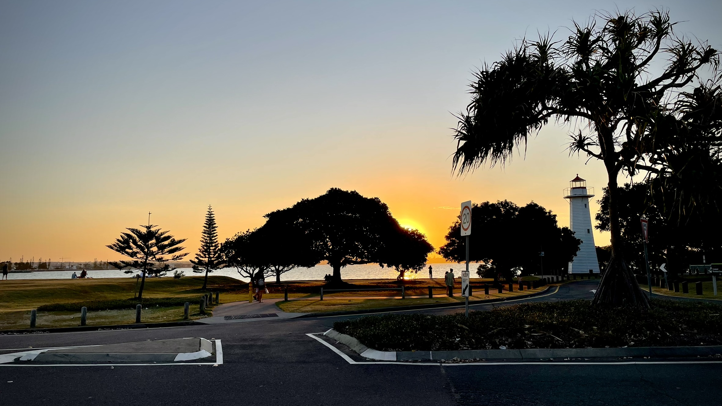 The lighthouse at Cleveland Point silhouetted against a sunset over Moreton Bay